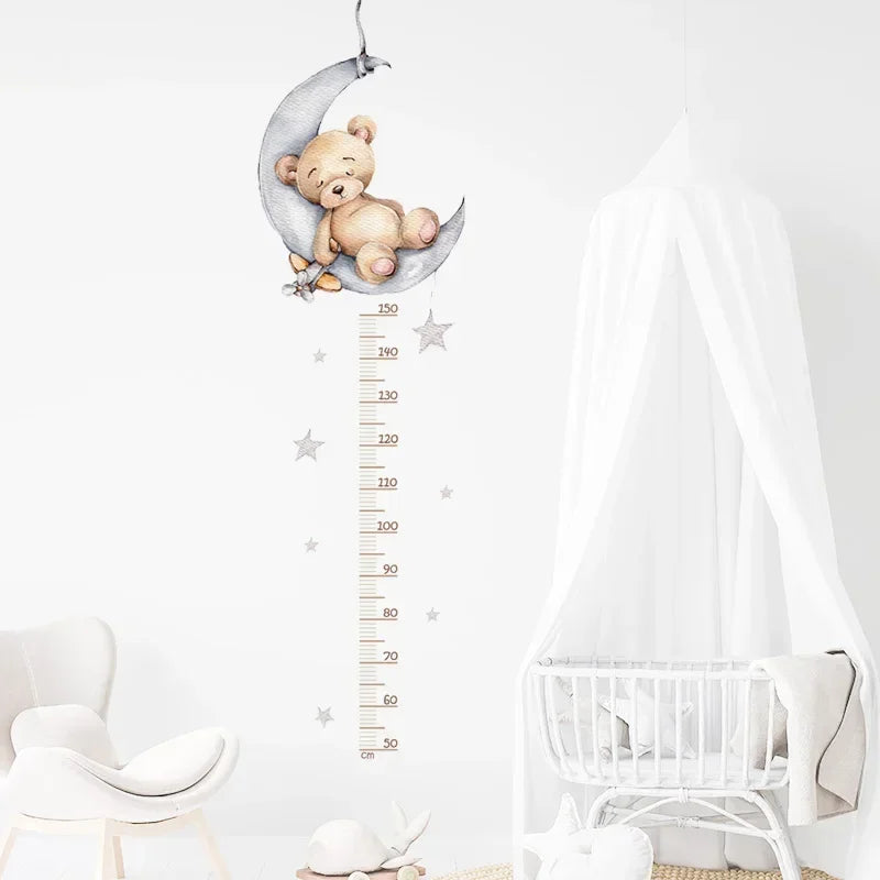 Sticker toise ourson assoupi sur un croissant de lune dans une chambre bébé blanche avec berceau