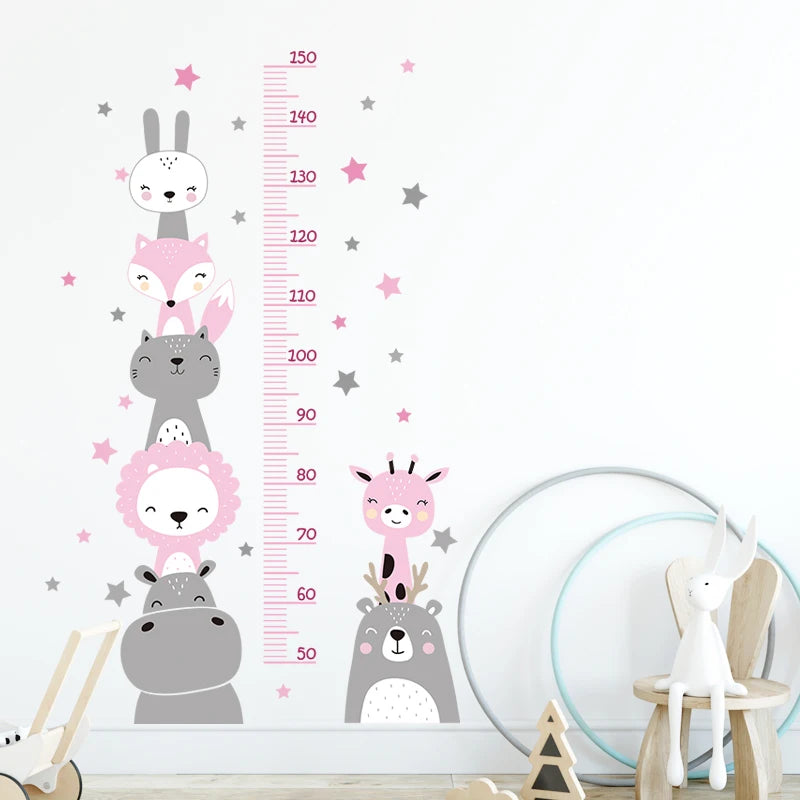 Toise murale renard, chat et lion rose poudré et gris avec étoiles roses sur un mur blanc, près d'une lampe lapin