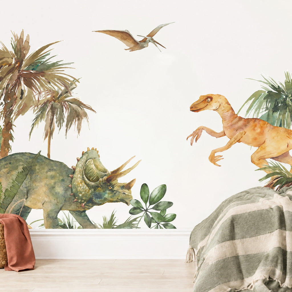 Grand sticker mural dinosaures aquarelle dans une chambre de garçon, tricératops vert olive et raptor ocre près d'un lit au plaid vert sauge
