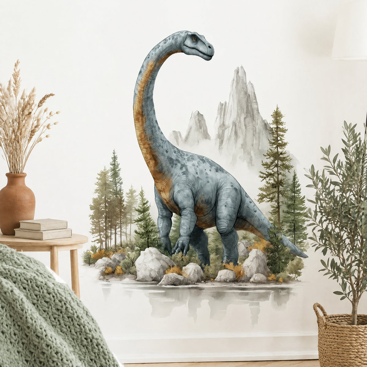 Sticker dinosaure à long cou gris-bleu et ocre sur un mur blanc de chambre, à côté d'un guéridon en chêne clair et d'un olivier en pot