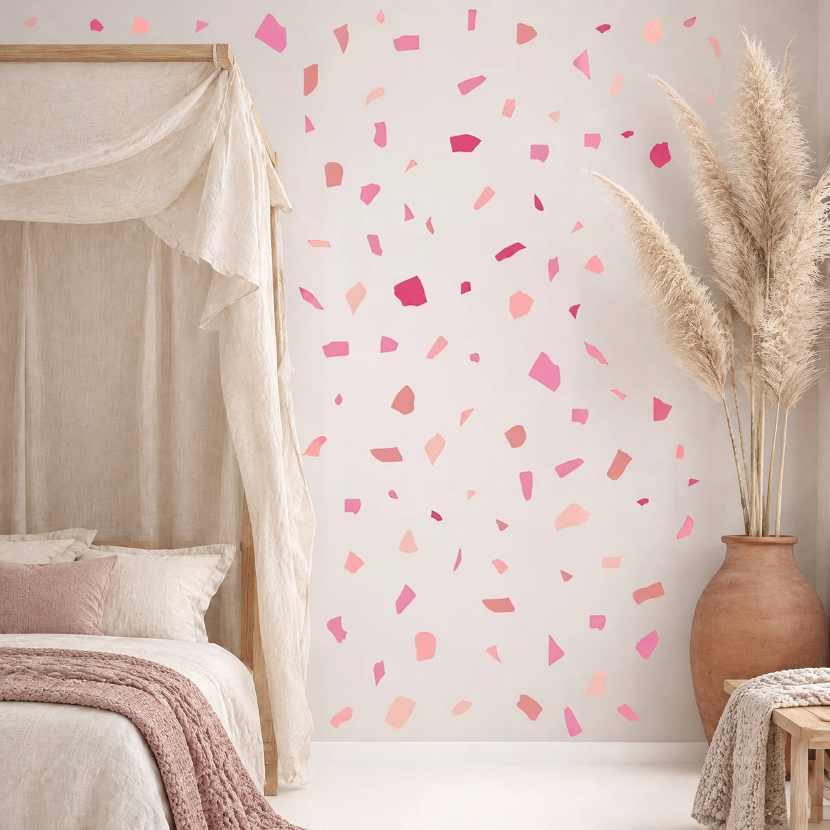 Stickers terrazzo roses dispersés au mur d'une chambre, à côté d'un lit à baldaquin en lin naturel et de pampas