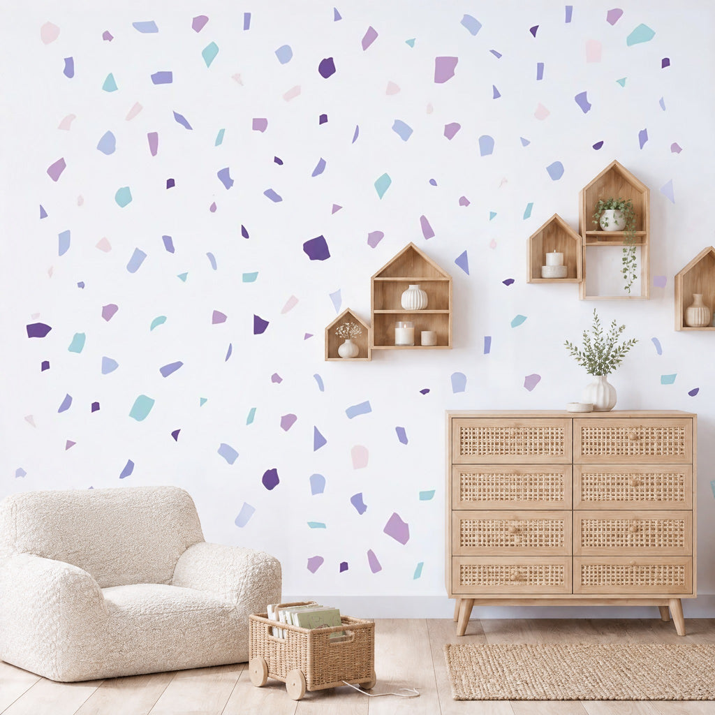 Stickers terrazzo lavande et vert d'eau au mur d'un salon, au-dessus d'une commode en chêne canné et d'étagères maisons en bois