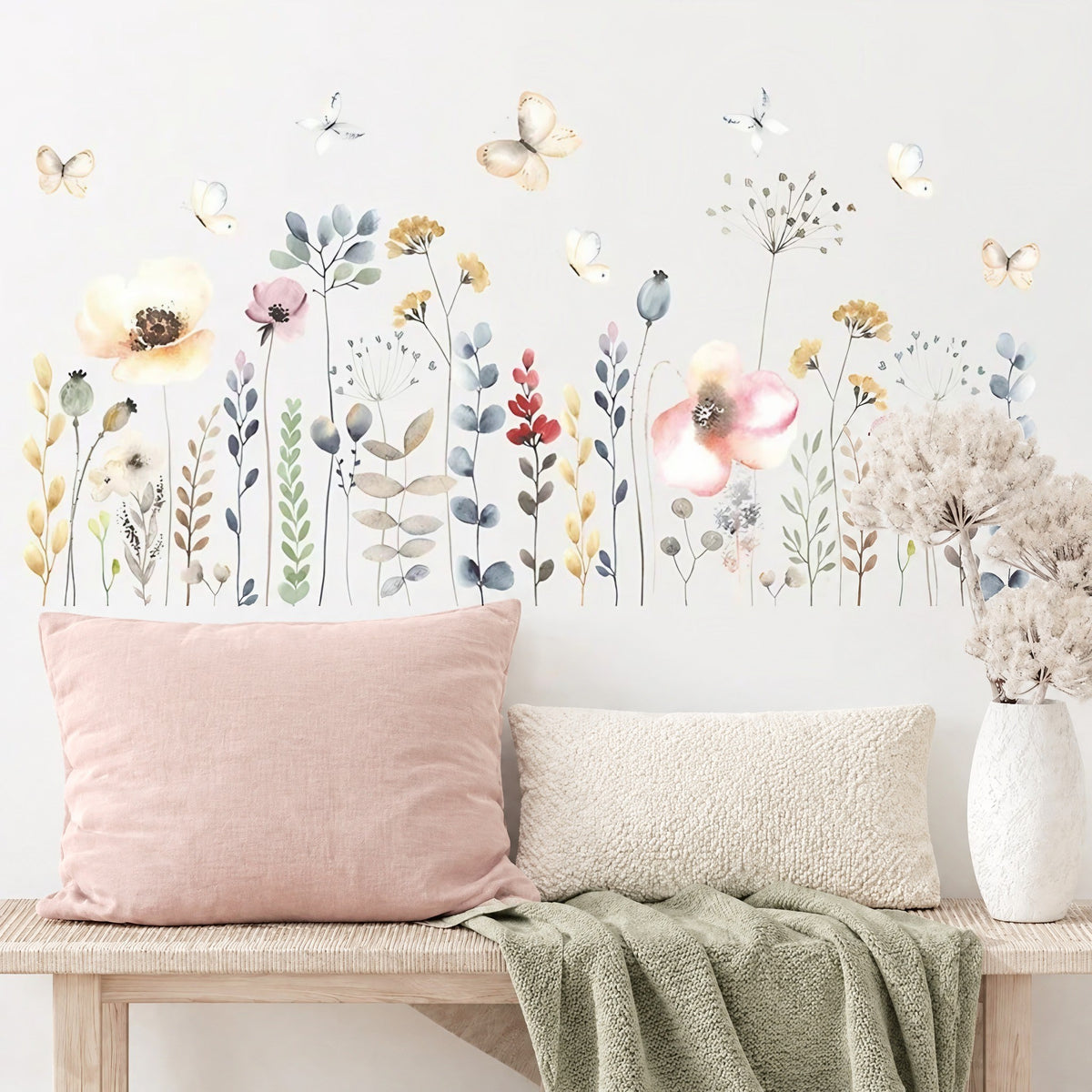 Frise de fleurs sauvages et papillons à l'aquarelle au-dessus d'un banc en bois clair avec coussins rose poudré et crème