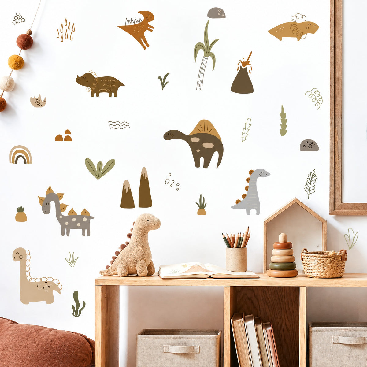 Stickers dinosaures bohème au-dessus d'un bureau d'enfant en bois avec carnet de dessin, pot de crayons et peluche dinosaure