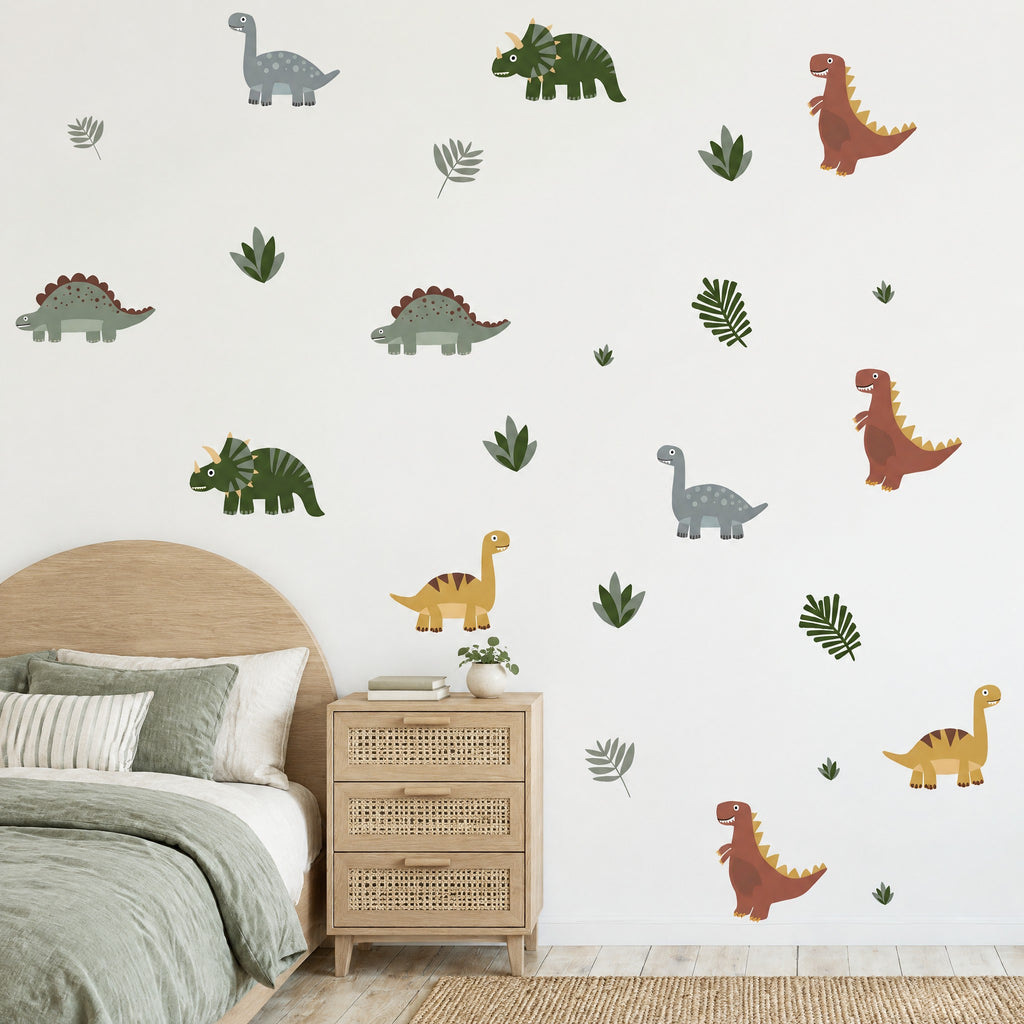 Stickers muraux dinosaures cartoon et feuilles sur un mur blanc de chambre de garçon, au-dessus d'un lit en chêne et d'une commode cannée