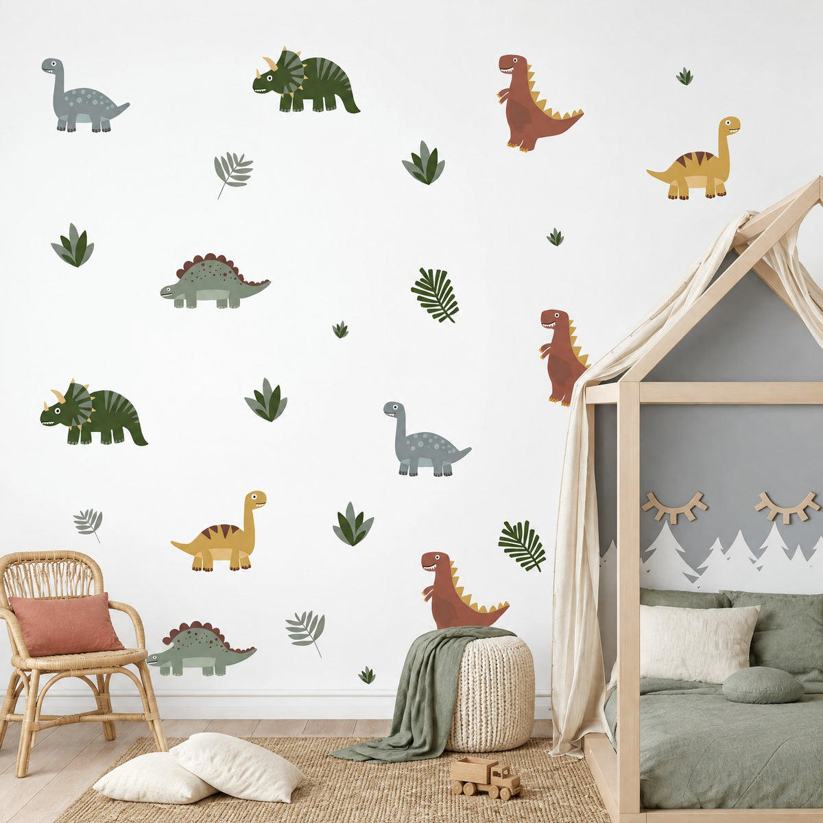 Stickers dinosaures et feuilles répartis sur le mur d'une chambre de garçon, lit cabane en bois, fauteuil en rotin et pouf tricoté crème