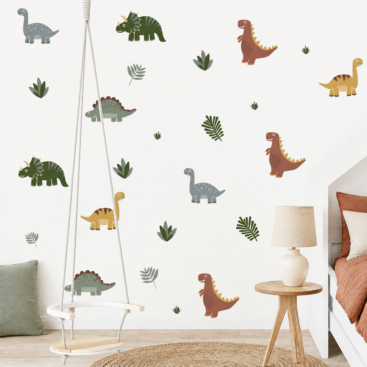 Stickers muraux dinosaures et feuilles dans une chambre de garçon avec balançoire, table d'appoint en chêne et lampe en céramique