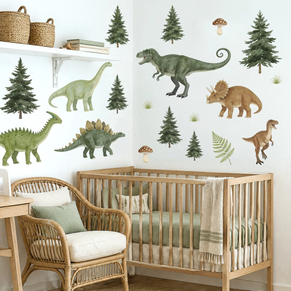 Stickers muraux dinosaures et sapins en aquarelle au-dessus d'un lit à barreaux en chêne clair dans une chambre de bébé, près d'un fauteuil en rotin