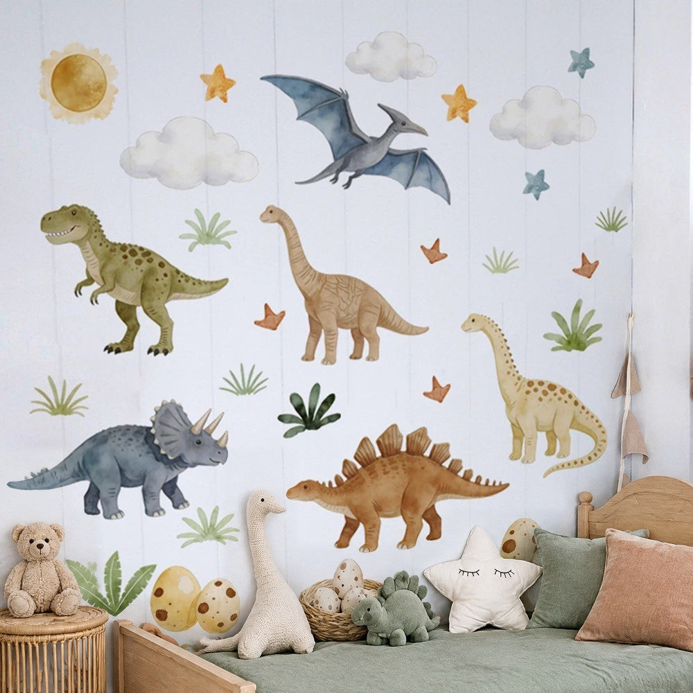 Stickers muraux dinosaures pastel au-dessus d'un lit d'enfant en bois clair au linge vert sauge : T-rex, tricératops, ptérodactyle, soleil et nuages