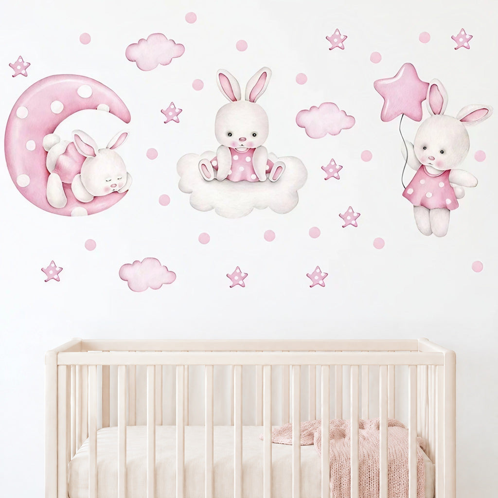 Composition de stickers lapins, lune et étoiles roses au-dessus d'un lit bébé à barreaux crème