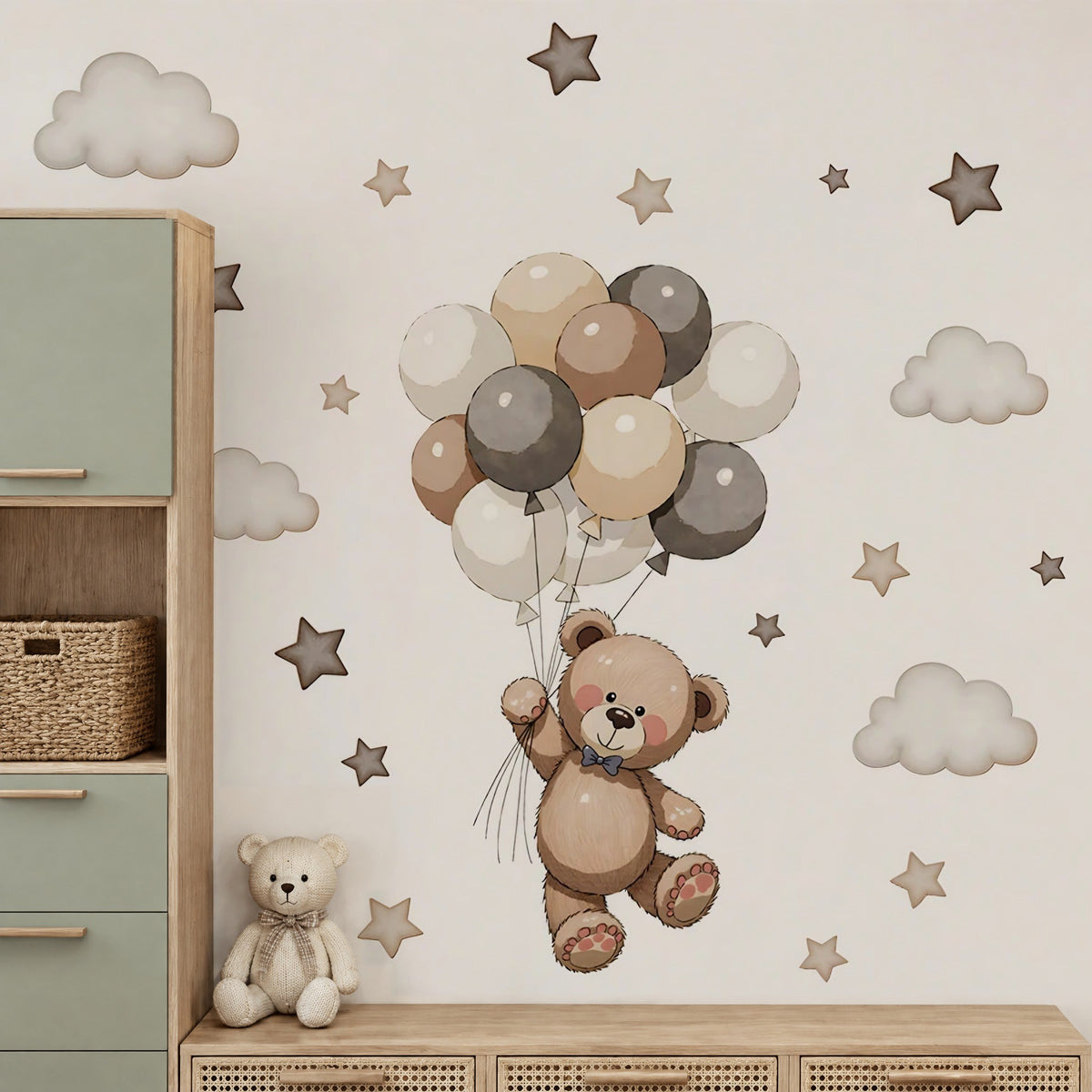 Stickers muraux ourson, ballons, étoiles et nuages dans une chambre de bébé près d'une armoire vert sauge et d'un buffet canné