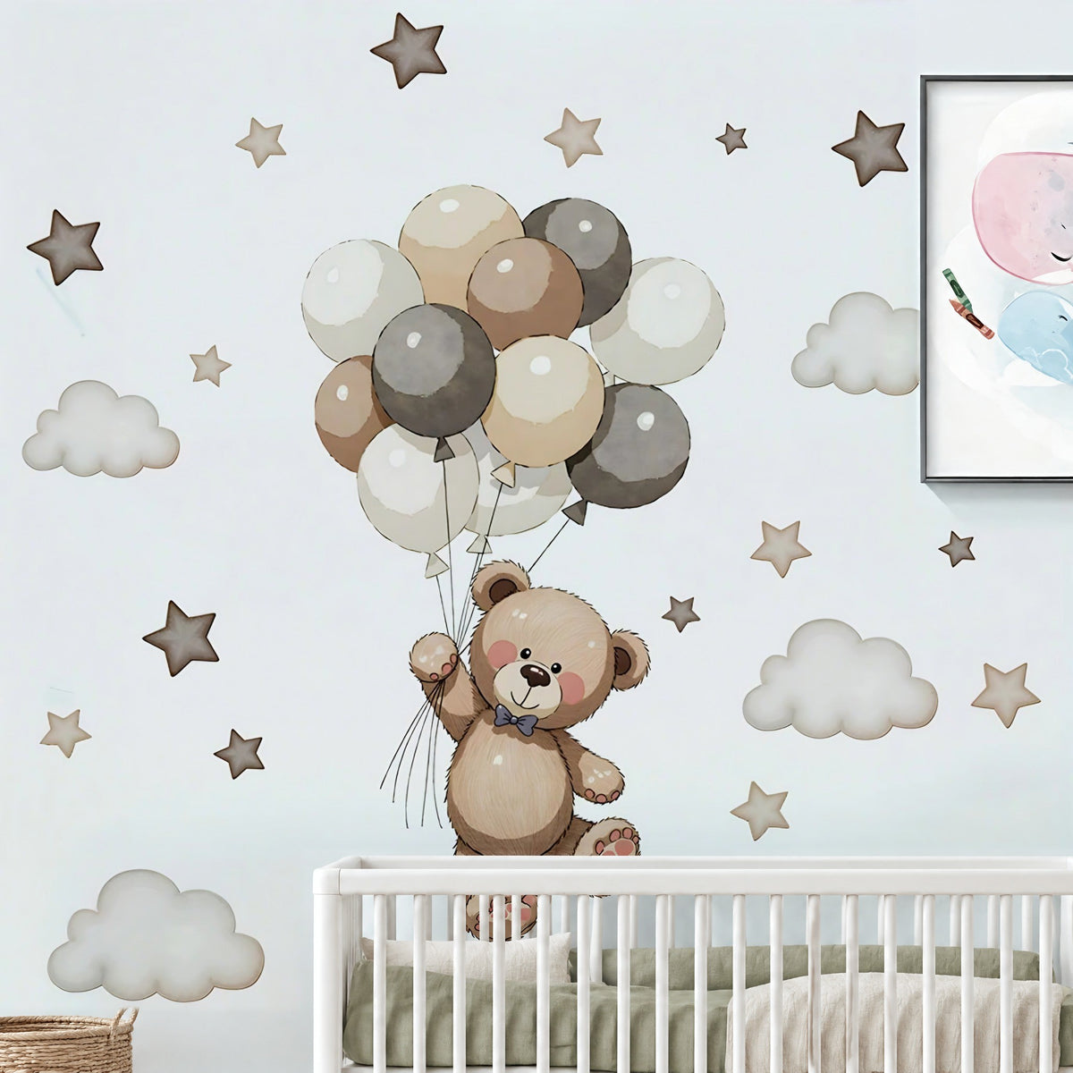 Stickers muraux ourson et ballons au-dessus d'un lit bébé à barreaux blanc avec linge vert sauge