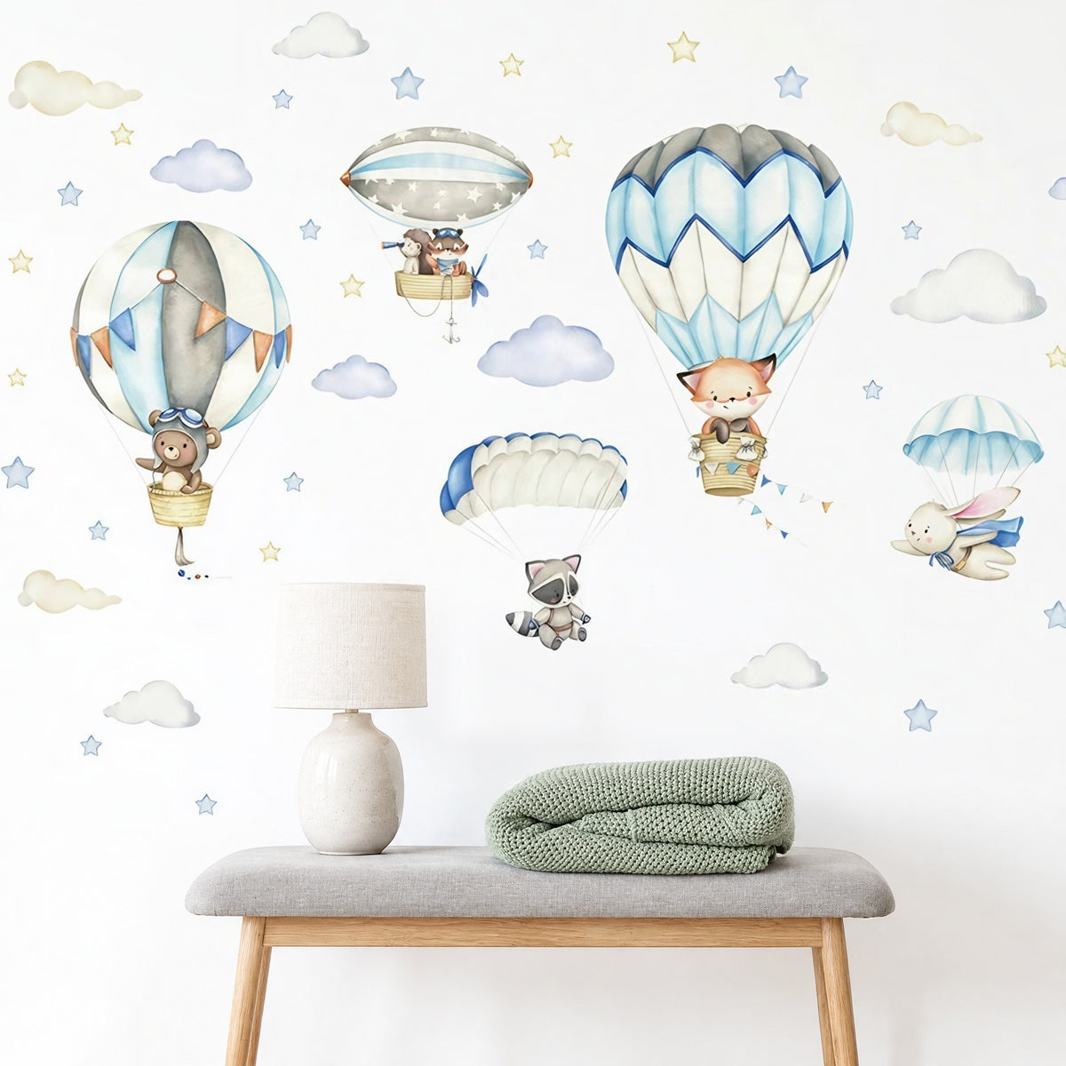 Composition renard, ourson et dirigeable étoilé au-dessus d'un banc en bois et d'une lampe en céramique dans une chambre de bébé