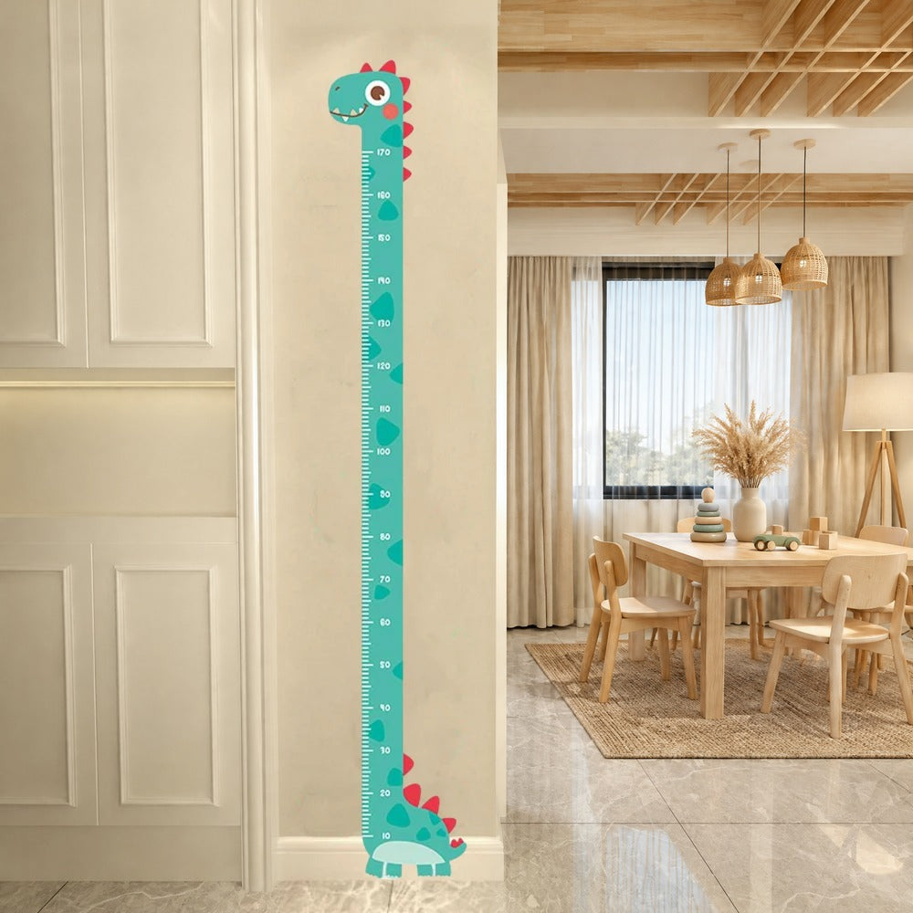 Sticker toise dinosaure vert d'eau sur un mur beige, à l'entrée d'une salle de jeux avec table en bois clair et suspensions en rotin