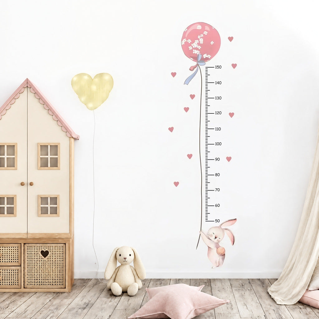 Sticker toise lapin et ballon rose dans une chambre de fille, à côté d'une armoire maison en bois clair et d'un lapin en peluche