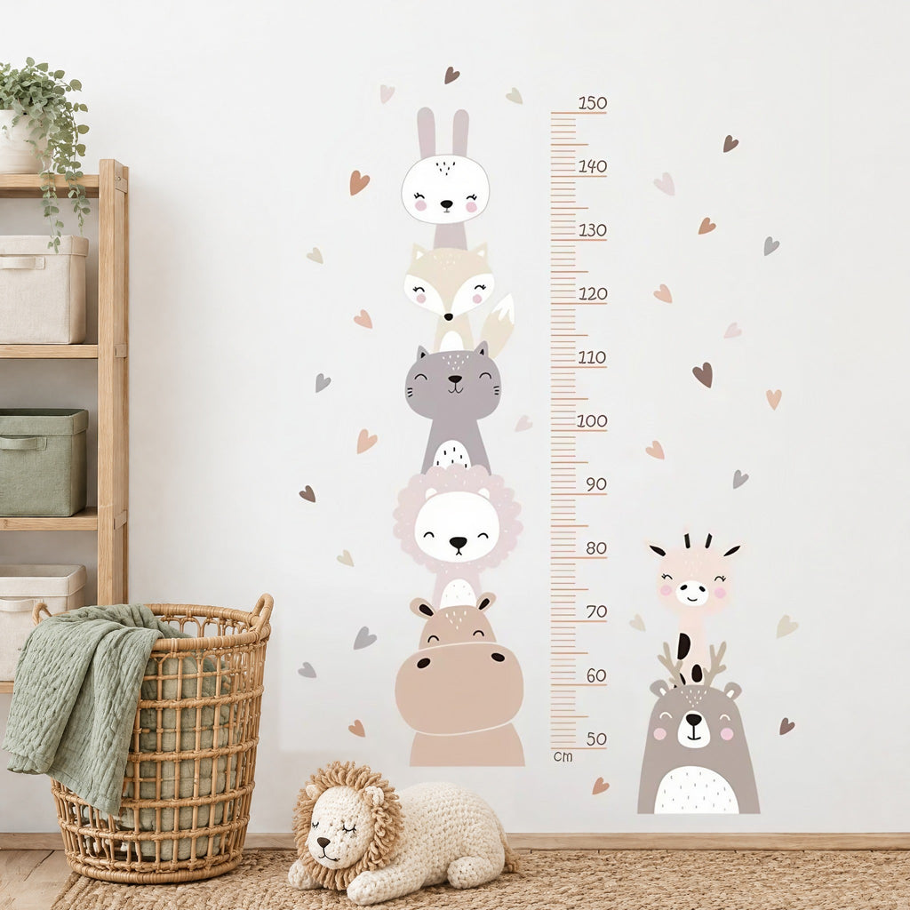 Stickers muraux toise lion, girafe et cœurs bohème dans une chambre de bébé, près d'un panier en rotin et d'un lion en tricot
