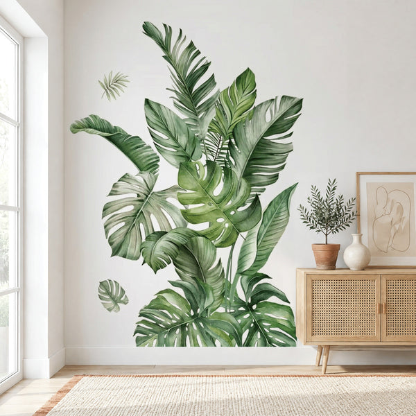 Stickers muraux végétal tropical, grandes feuilles de monstera et de bananier, à côté d'un buffet en chêne canné dans un salon lumineux
